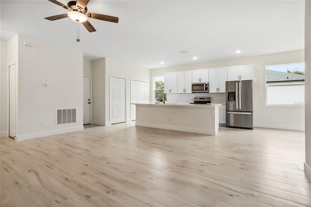 kitchen with stainless steel appliances, visible vents, open floor plan, white cabinetry, and light wood-type flooring