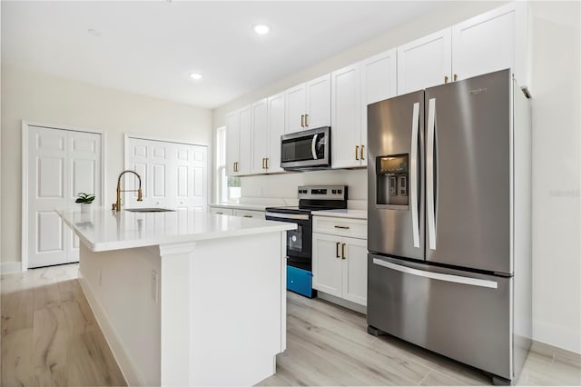 kitchen featuring white cabinets, an island with sink, appliances with stainless steel finishes, light countertops, and a sink