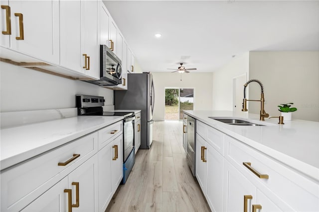 kitchen featuring ceiling fan, light wood-style flooring, stainless steel appliances, white cabinetry, and a sink