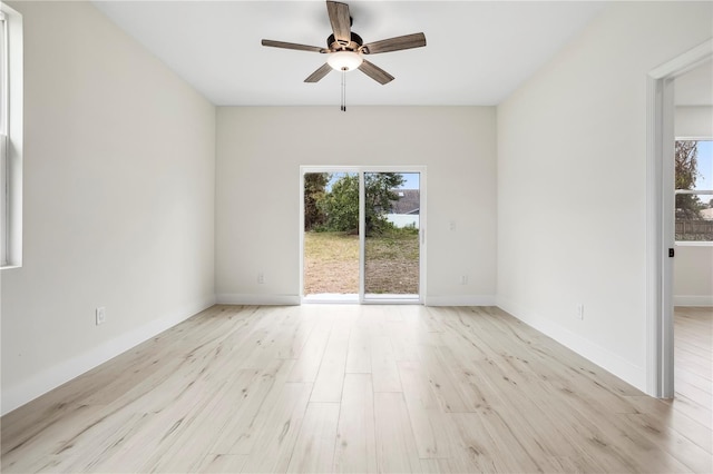 spare room with plenty of natural light, wood finished floors, a ceiling fan, and baseboards