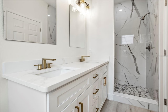 bathroom with a sink, a marble finish shower, and double vanity