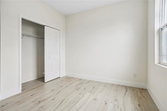 unfurnished bedroom featuring a closet, baseboards, and wood finished floors