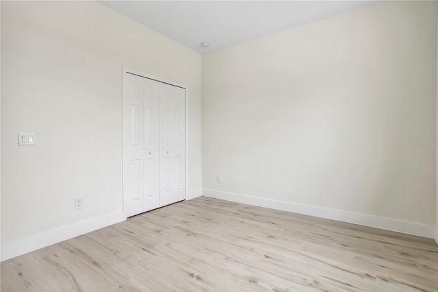 unfurnished bedroom with light wood finished floors, a closet, and baseboards