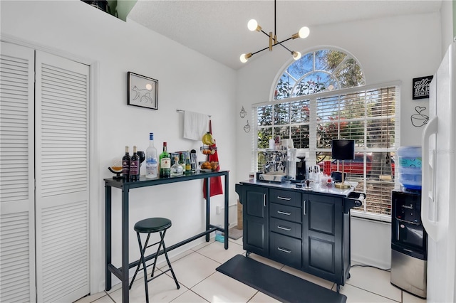 102 Ethan Ave, Davenport, FL 33897 - bar area featuring lofted ceiling, white refrigerator with ice dispenser, light tile patterned floors, and a chandelier