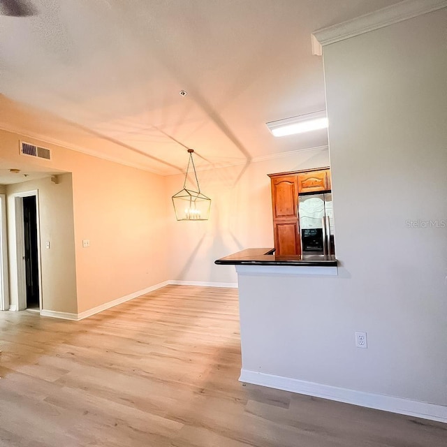 kitchen featuring dark countertops, visible vents, brown cabinetry, light wood-style floors, and stainless steel fridge