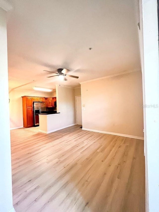 unfurnished living room featuring light wood-style floors, ornamental molding, baseboards, and ceiling fan