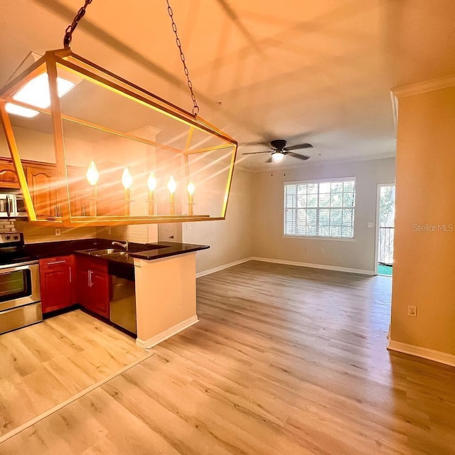 kitchen with stainless steel appliances, dark countertops, a sink, and light wood-style floors