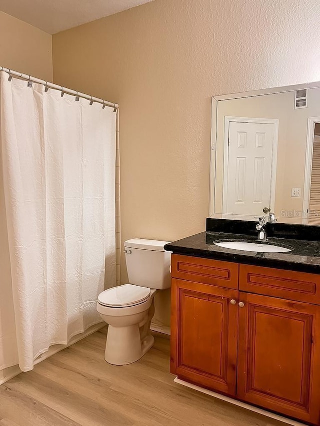 full bath featuring visible vents, a shower with shower curtain, toilet, vanity, and wood finished floors