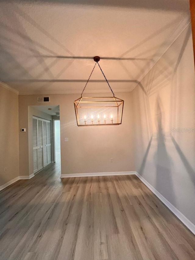 unfurnished room featuring ornamental molding, visible vents, baseboards, and wood finished floors