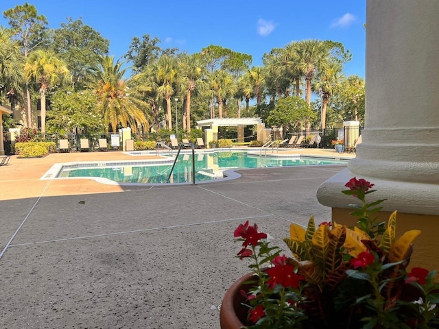 community pool with a patio area and fence