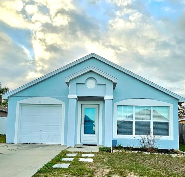 ranch-style house featuring a garage, driveway, and stucco siding