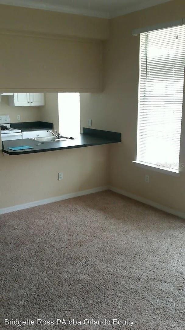 kitchen with white electric range, a sink, and baseboards