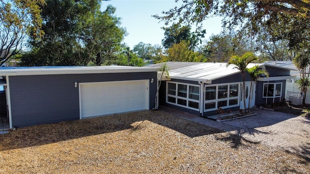 view of front facade featuring gravel driveway, a sunroom, and an attached garage