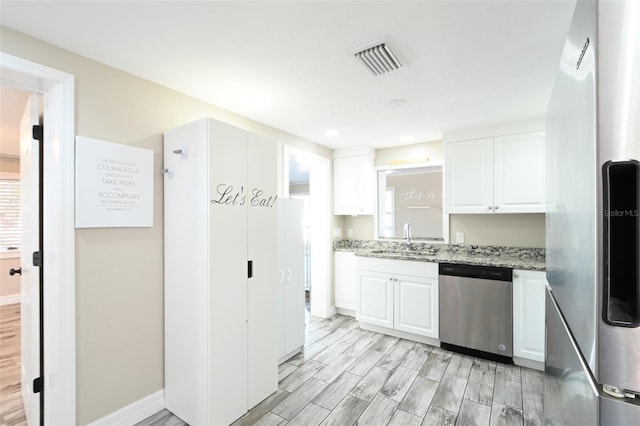 kitchen featuring visible vents, appliances with stainless steel finishes, wood tiled floor, white cabinetry, and a sink