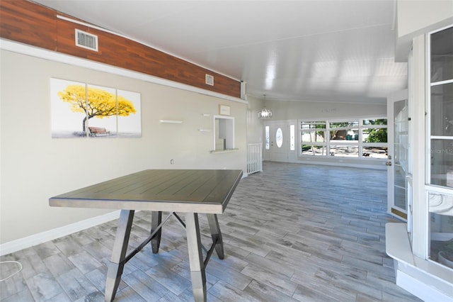 interior space with vaulted ceiling, wood finished floors, visible vents, and baseboards