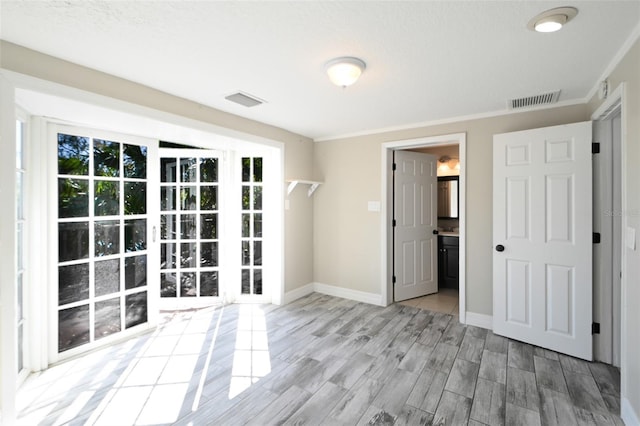 spare room featuring baseboards, crown molding, visible vents, and wood finished floors