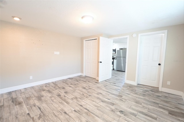 unfurnished room with light wood-type flooring and baseboards