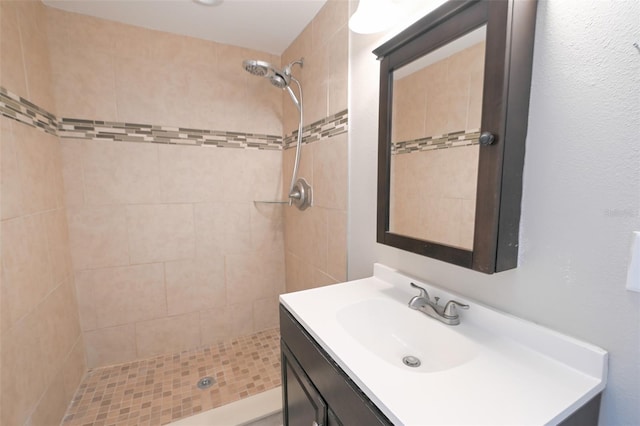 full bath featuring tiled shower and vanity