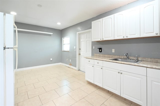 kitchen featuring freestanding refrigerator, white cabinets, and a sink