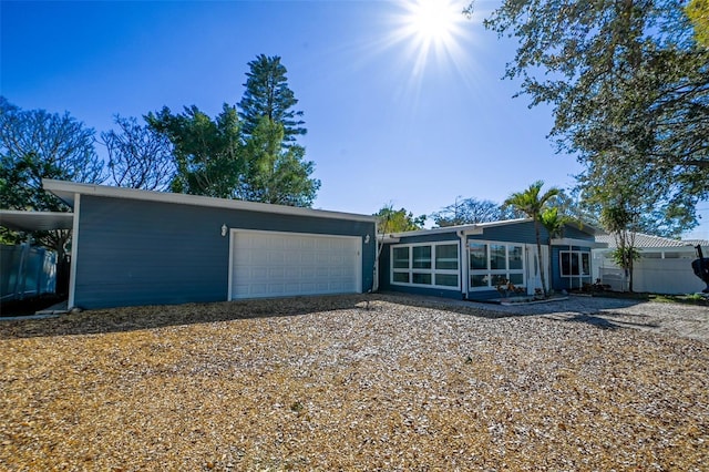 view of front facade with a garage, a sunroom, and driveway