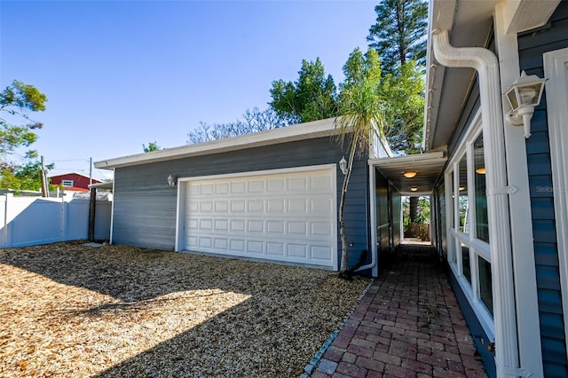 garage featuring driveway and fence