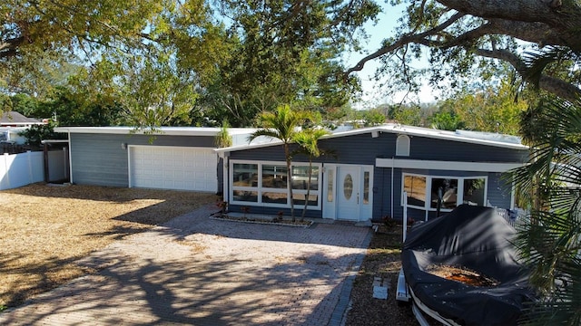 mid-century modern home with a garage, driveway, and fence