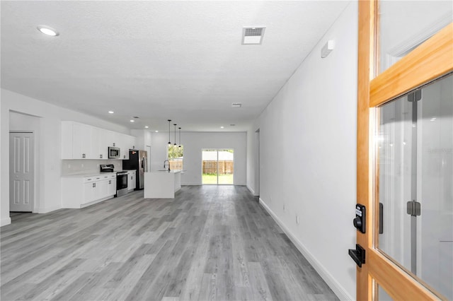 unfurnished living room featuring visible vents, recessed lighting, light wood-style flooring, and baseboards