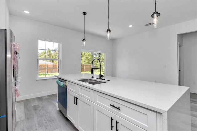 kitchen with appliances with stainless steel finishes, a sink, light wood finished floors, white cabinetry, and recessed lighting