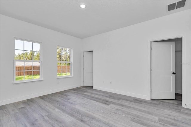 unfurnished room featuring visible vents, light wood finished floors, and baseboards