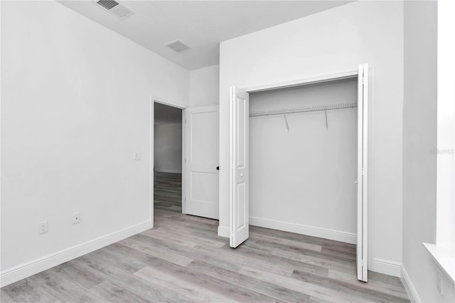 unfurnished bedroom featuring visible vents, wood finished floors, and a closet