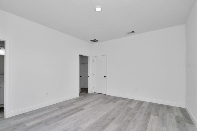 spare room with visible vents, light wood finished floors, and baseboards