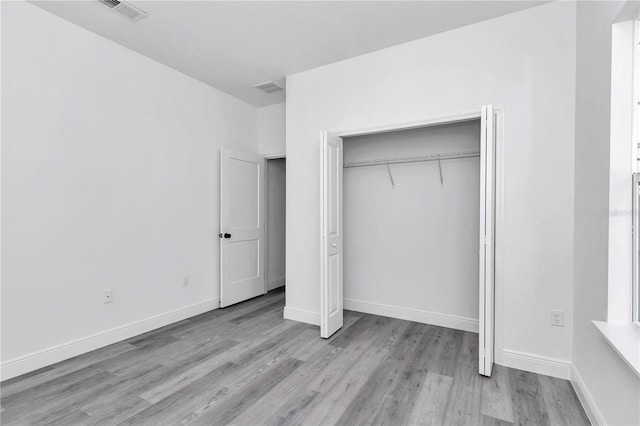 unfurnished bedroom featuring visible vents, baseboards, wood finished floors, and a closet