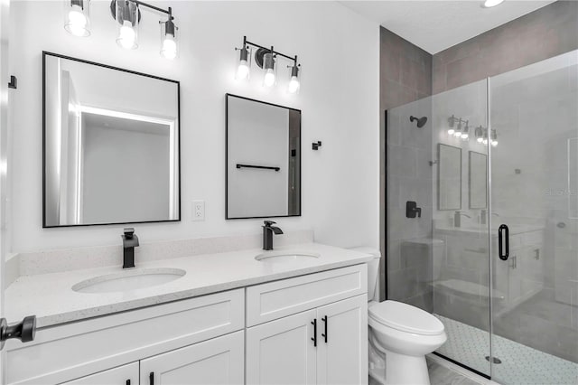 bathroom featuring double vanity, a sink, a stall shower, and toilet