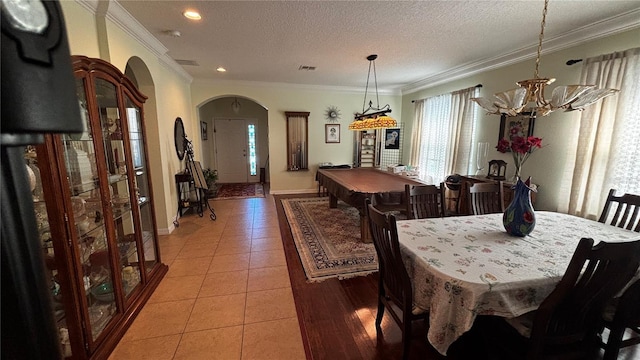 dining area featuring visible vents, arched walkways, ornamental molding, a textured ceiling, and light tile patterned flooring