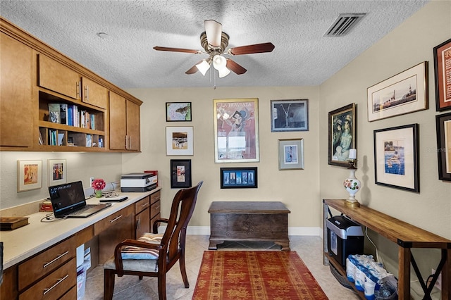 home office featuring built in desk, light tile patterned floors, visible vents, a ceiling fan, and a textured ceiling