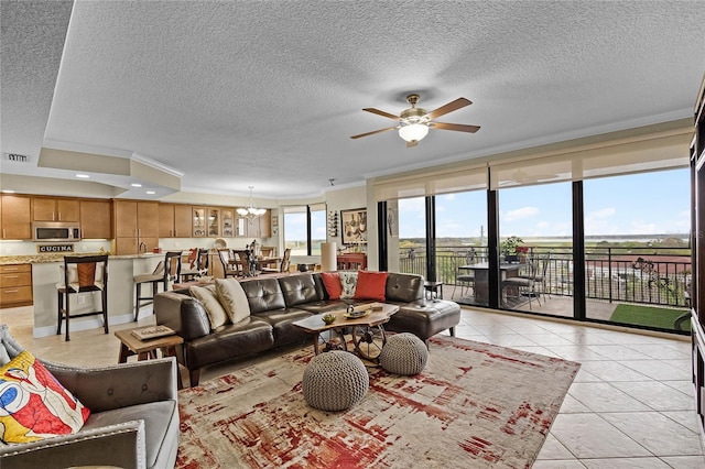 living area featuring ceiling fan with notable chandelier, crown molding, a textured ceiling, and light tile patterned floors