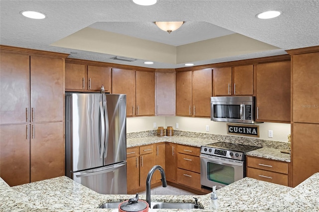 kitchen featuring visible vents, appliances with stainless steel finishes, brown cabinetry, and a sink