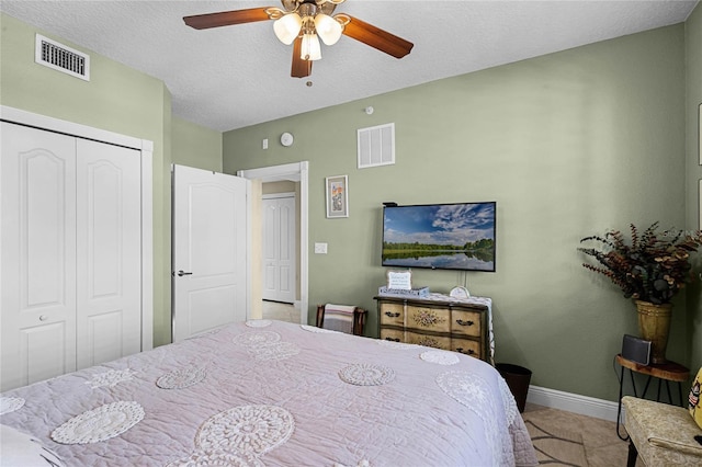 bedroom with a textured ceiling, a closet, visible vents, and baseboards