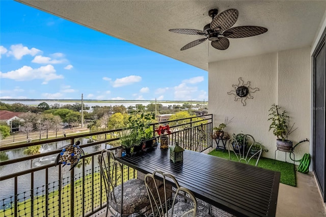 balcony featuring a water view and a ceiling fan