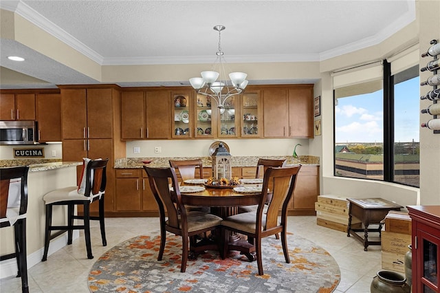 dining room with a chandelier, ornamental molding, a textured ceiling, and light tile patterned floors