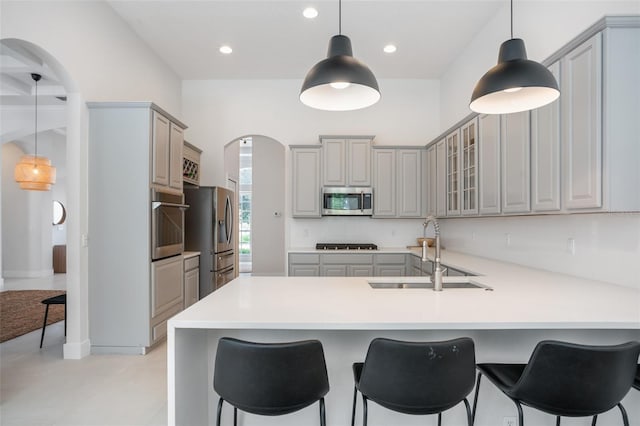 kitchen featuring a sink, stainless steel appliances, gray cabinetry, and a peninsula