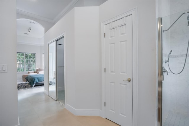 hall with crown molding, visible vents, arched walkways, and baseboards