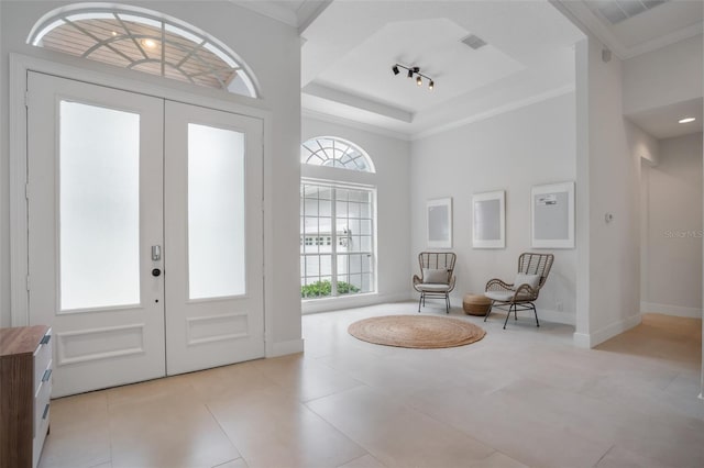 tiled foyer featuring a tray ceiling, french doors, visible vents, and ornamental molding