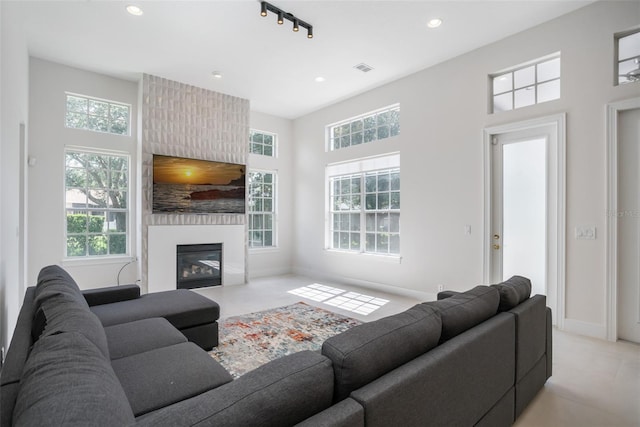 living area with a wealth of natural light, baseboards, a large fireplace, and recessed lighting