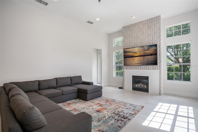 living room featuring baseboards, visible vents, a towering ceiling, and a large fireplace