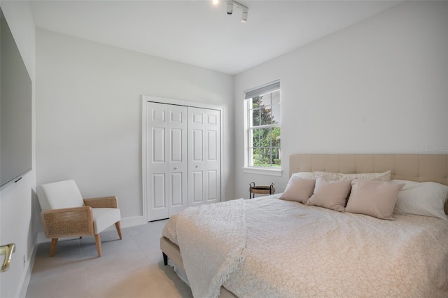 bedroom featuring track lighting, baseboards, and a closet