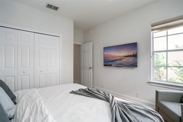 bedroom with a closet, visible vents, and baseboards