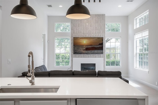 kitchen with light countertops, a large fireplace, plenty of natural light, and a sink