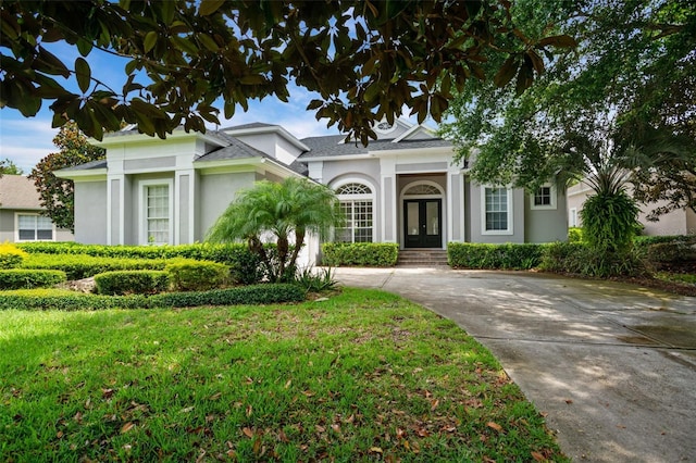 neoclassical home featuring concrete driveway, a front lawn, and stucco siding