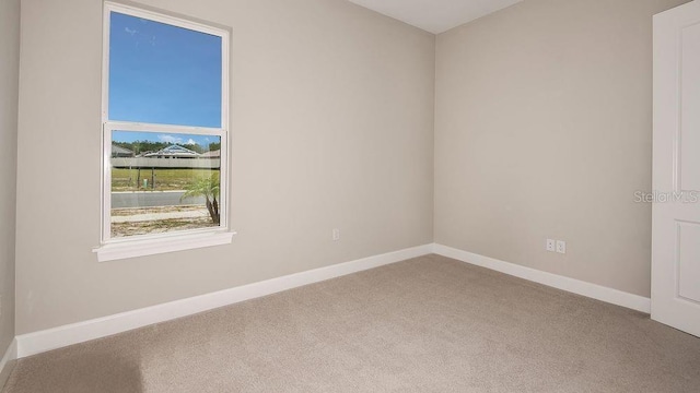 carpeted empty room featuring baseboards